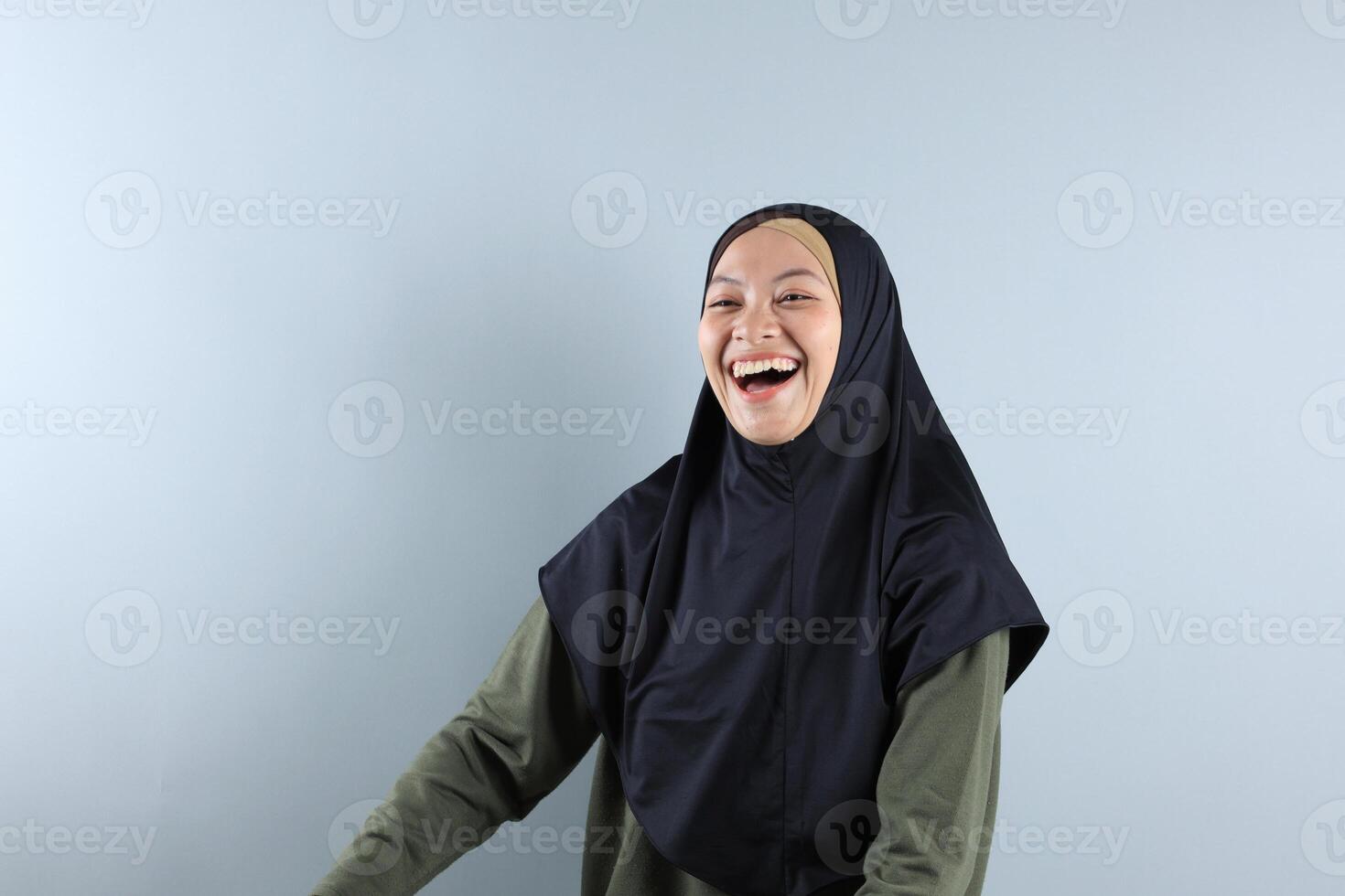 Beautiful Muslim Woman Wearing Black Hijab, Green Sage Blouse Smiling and Looking Back photo