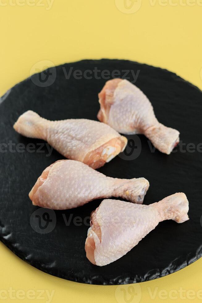 Raw Chicken Drumsticks on Black Plate photo