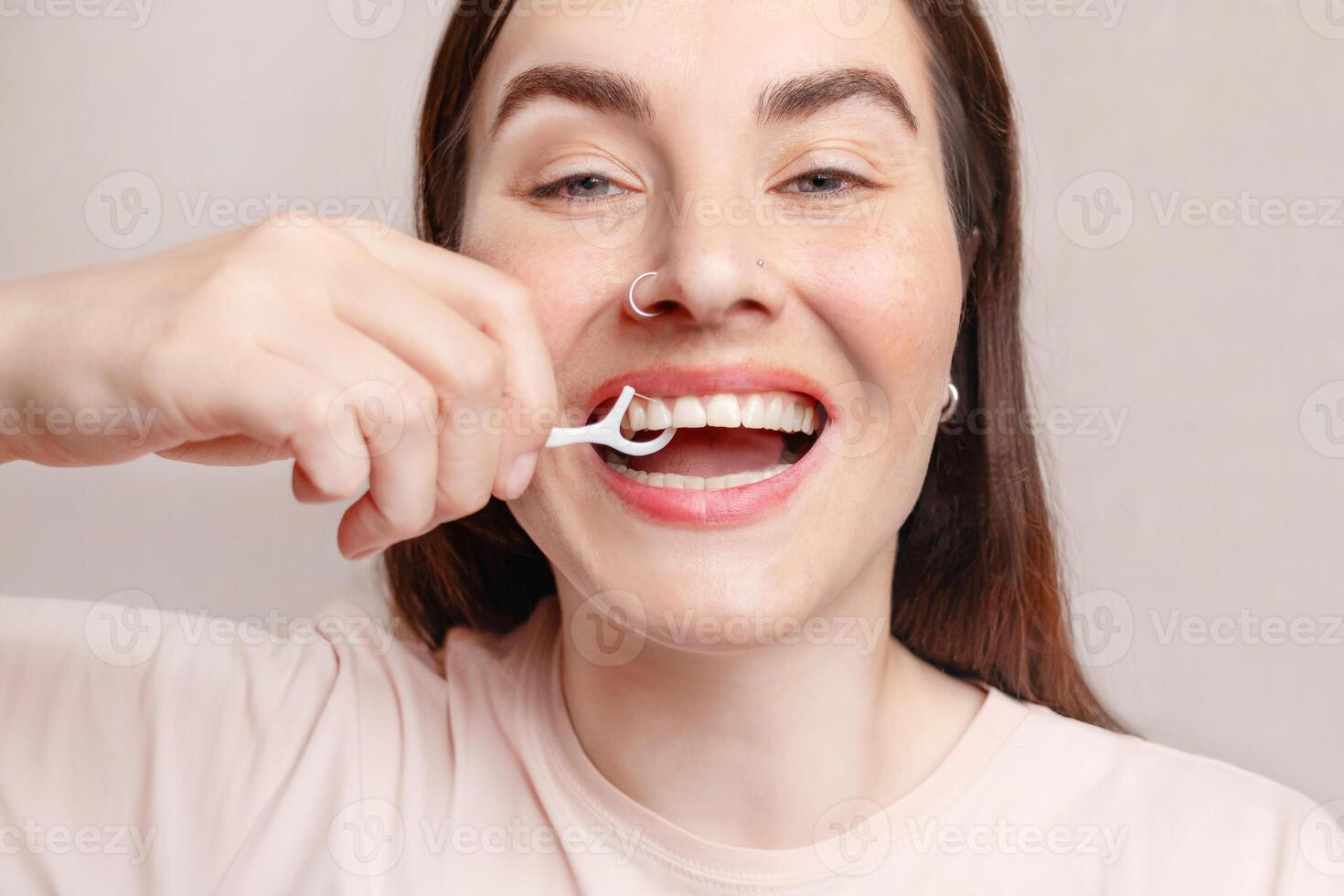 A woman uses dental floss on a stick, brushes her teeth. She is happy. The concept of healthy teeth, self-care photo