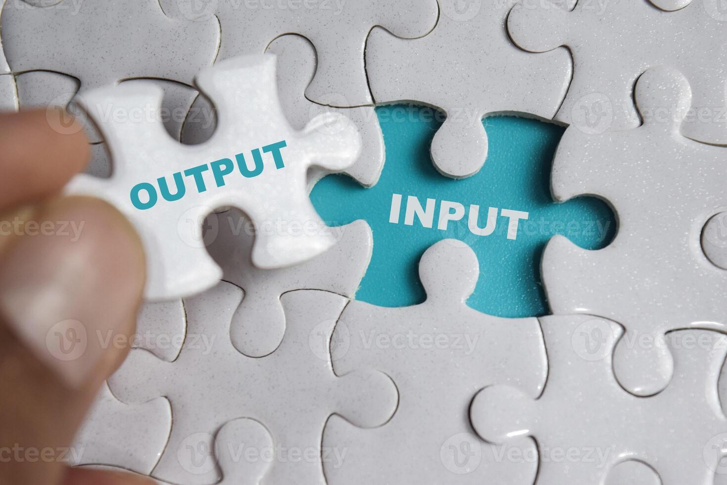 Hand holding piece of jigsaw puzzle with word Output or input. Business and finance concept photo