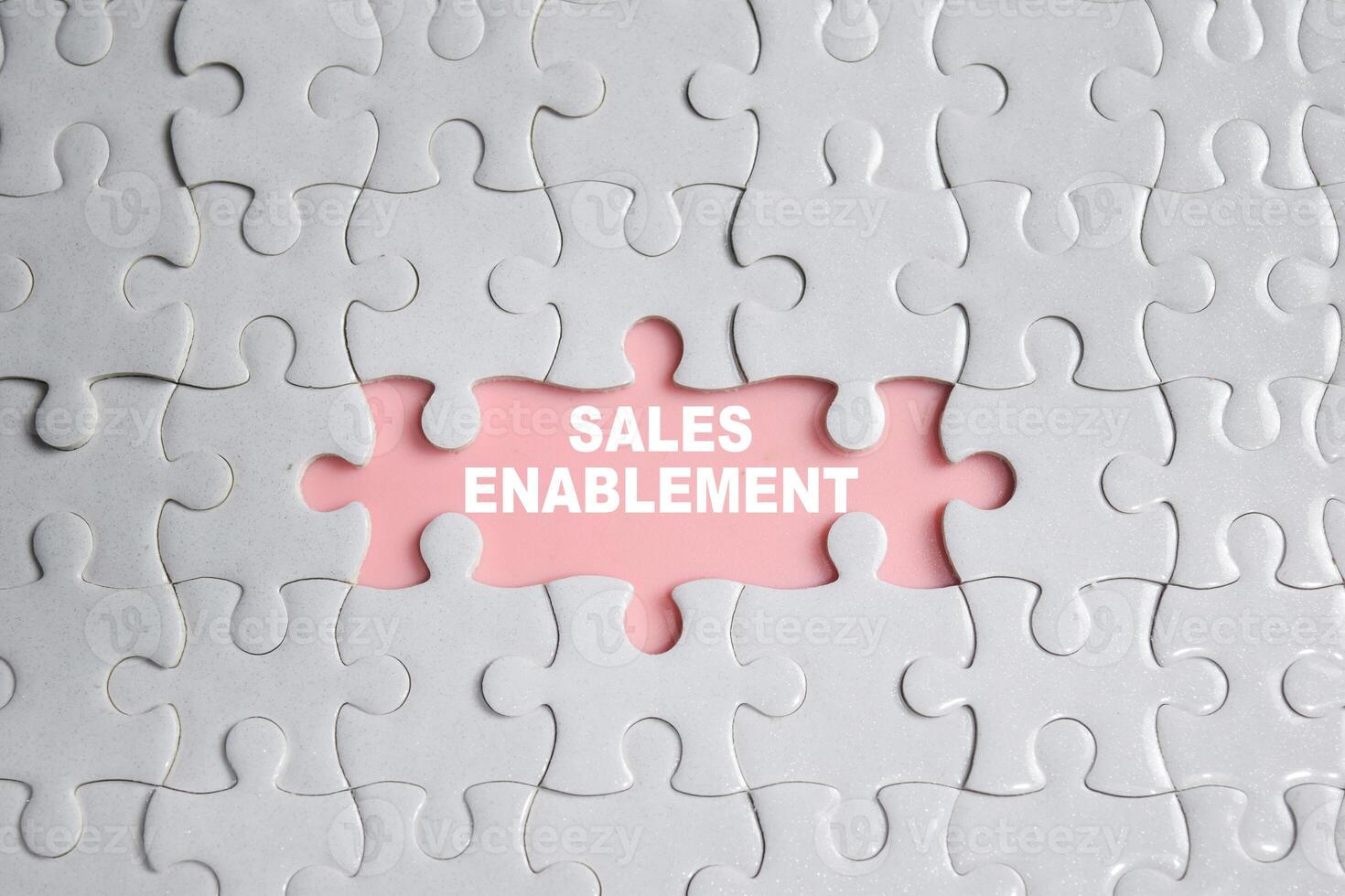 Hand holding piece of jigsaw puzzle with word Sales Enablement. Business and finance concept photo