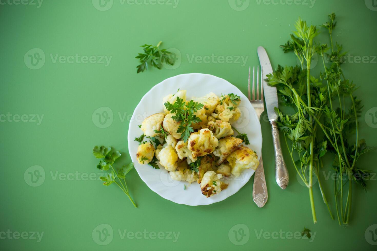 Top view of crispy cauliflower with parsley on a green background . photo