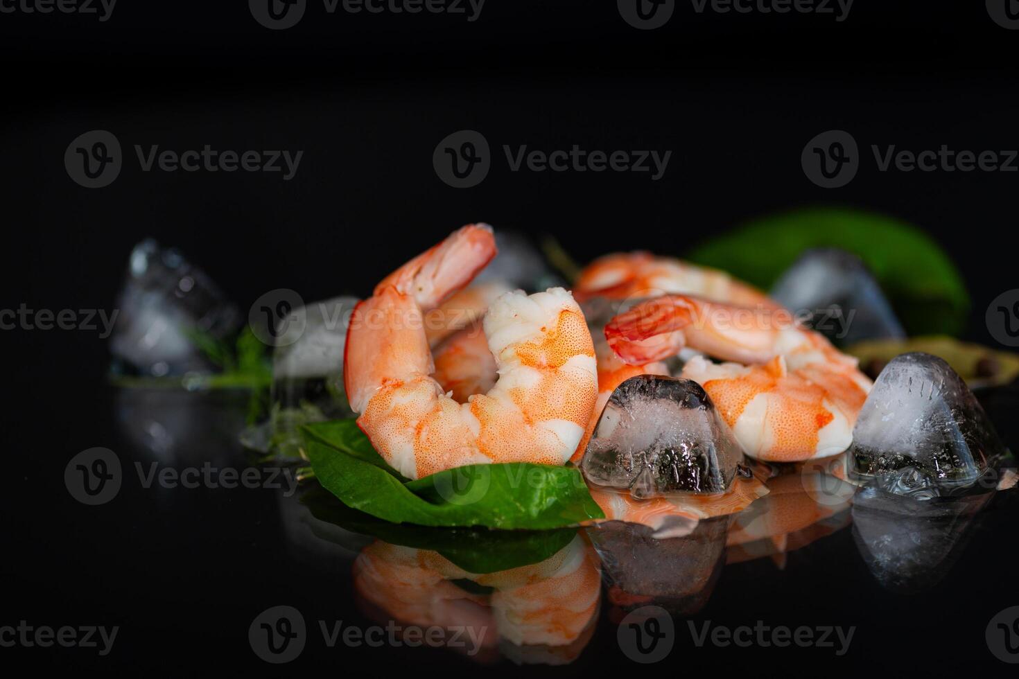 Boiled shrimp with ice and spices on a black background photo