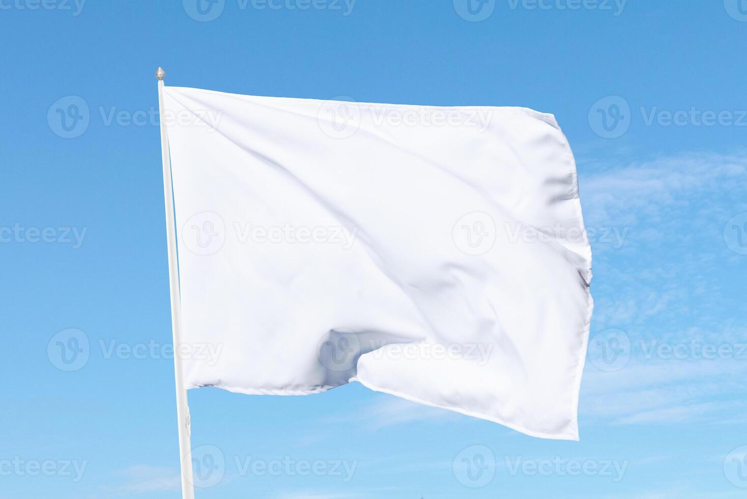 White flag billowing softly on a flagpole under sunny skies, perfect for themes of neutrality, announcements, or clean design aesthetics photo