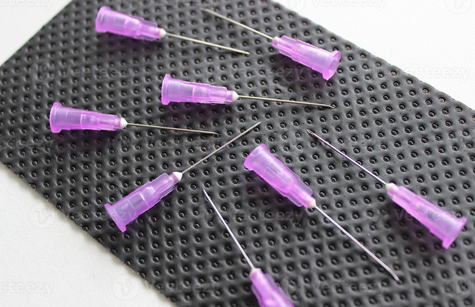 Open needles for disposable syringes are scattered on a black medical napkin photo