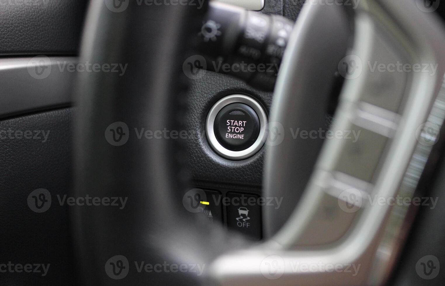 View of the electronic engine start button through the blurred steering wheel spokes photo