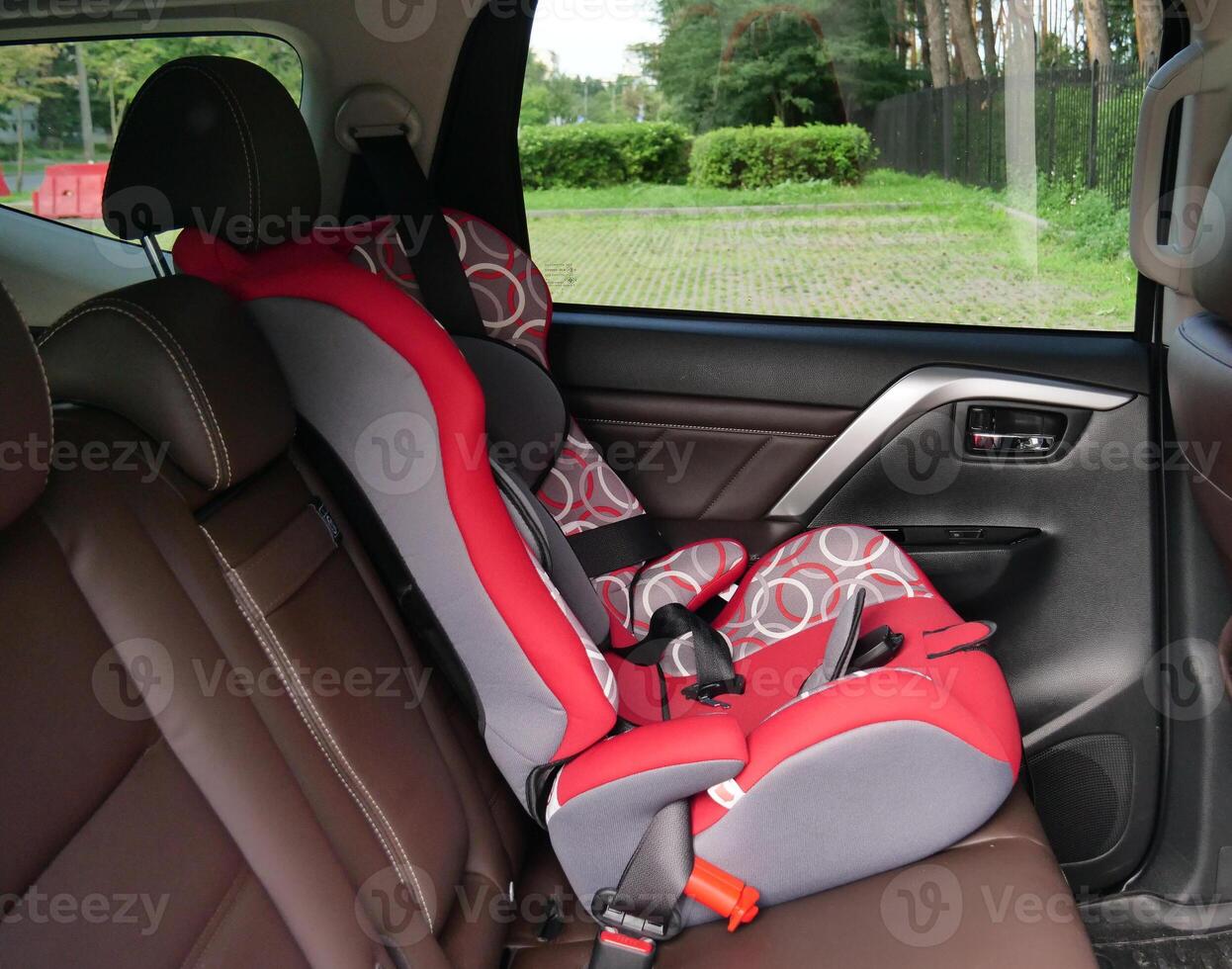 Red infant car seat in the back seat secured with standard seat belts photo
