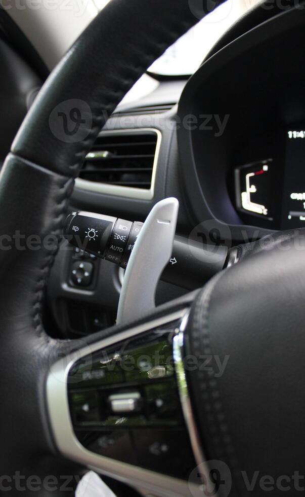 Gear shifter and headlight control lever under steering wheel of modern car photo