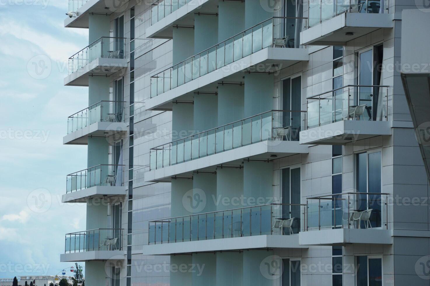 Facade of white modern street building with many glass balconies. Urban architecture. photo