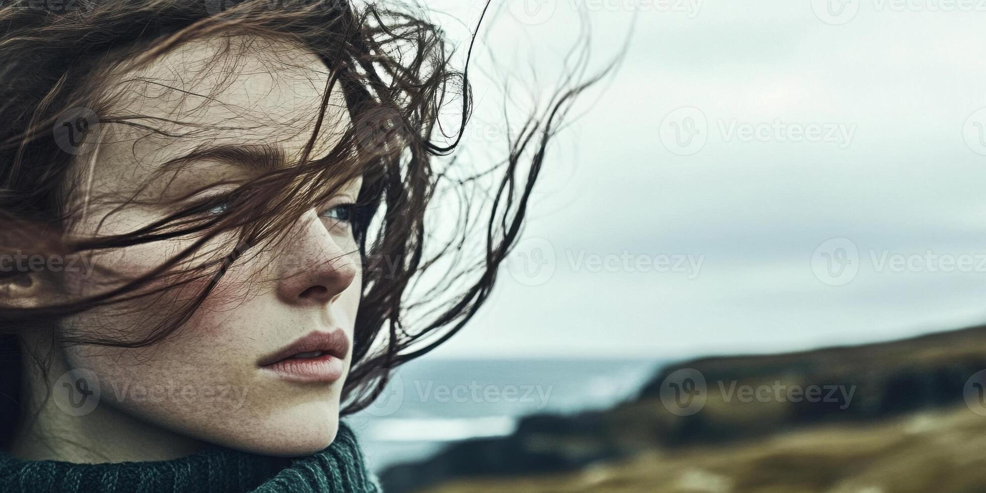 A WindSwept Portrait of a Thoughtful Young Woman Standing by the Beautiful Sea Shore photo