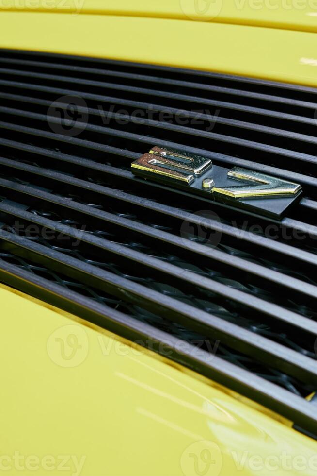 Yellow car with a black grill and a silver numbers 2.7 on it. Phone wallpaper. Vertical background. photo