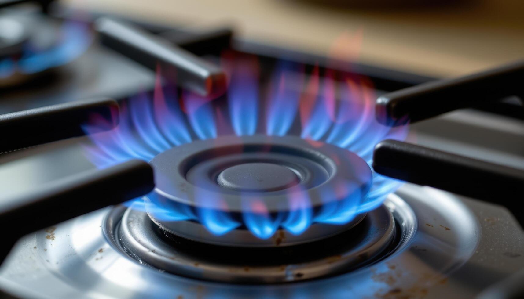 close up view of blue flames curling gently from a gas stove burner, casting faint shadows on the surrounding metal. photo