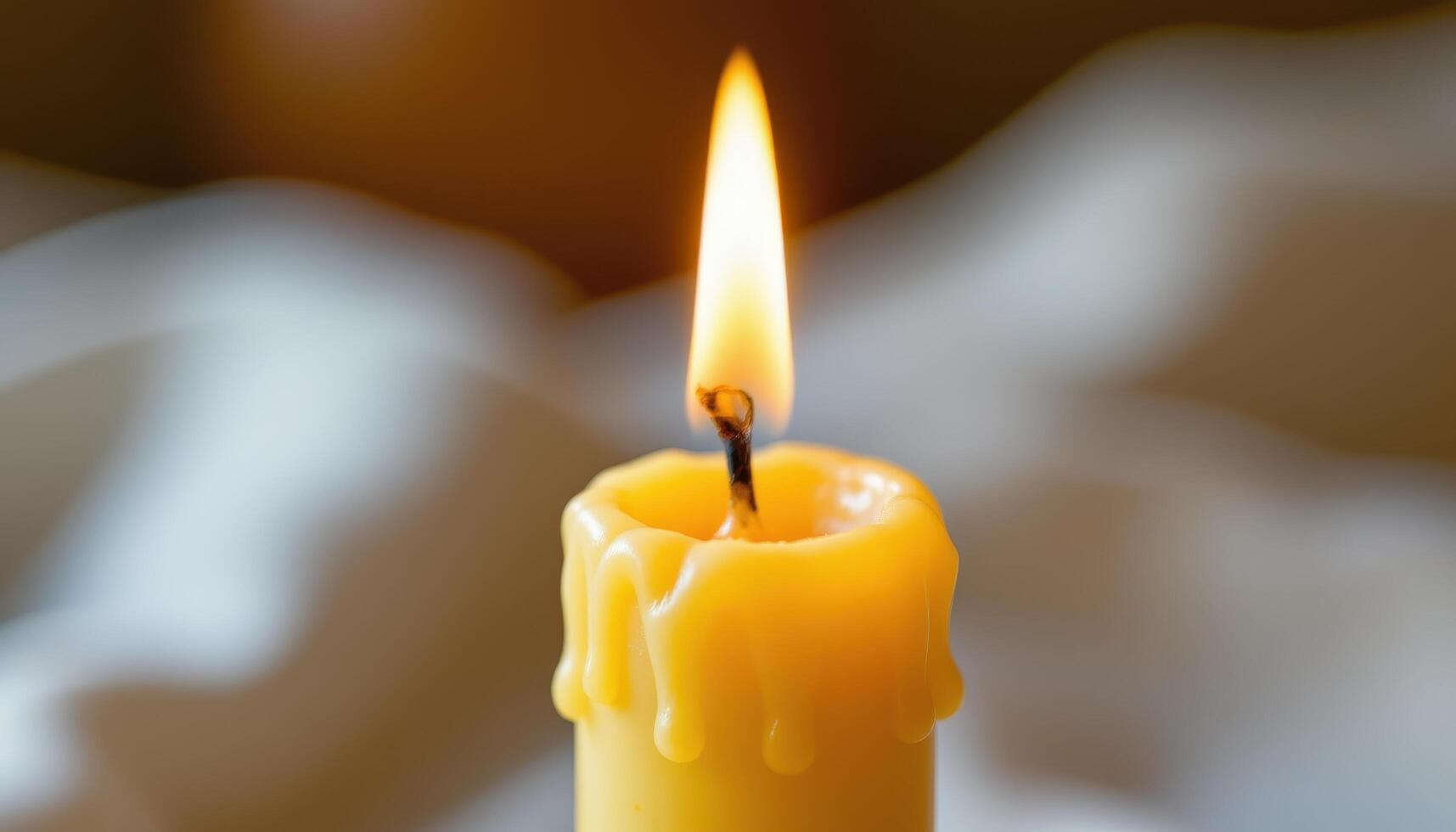 close up view of a single flame hovering atop a tall beeswax candle, surrounded by golden drips. photo