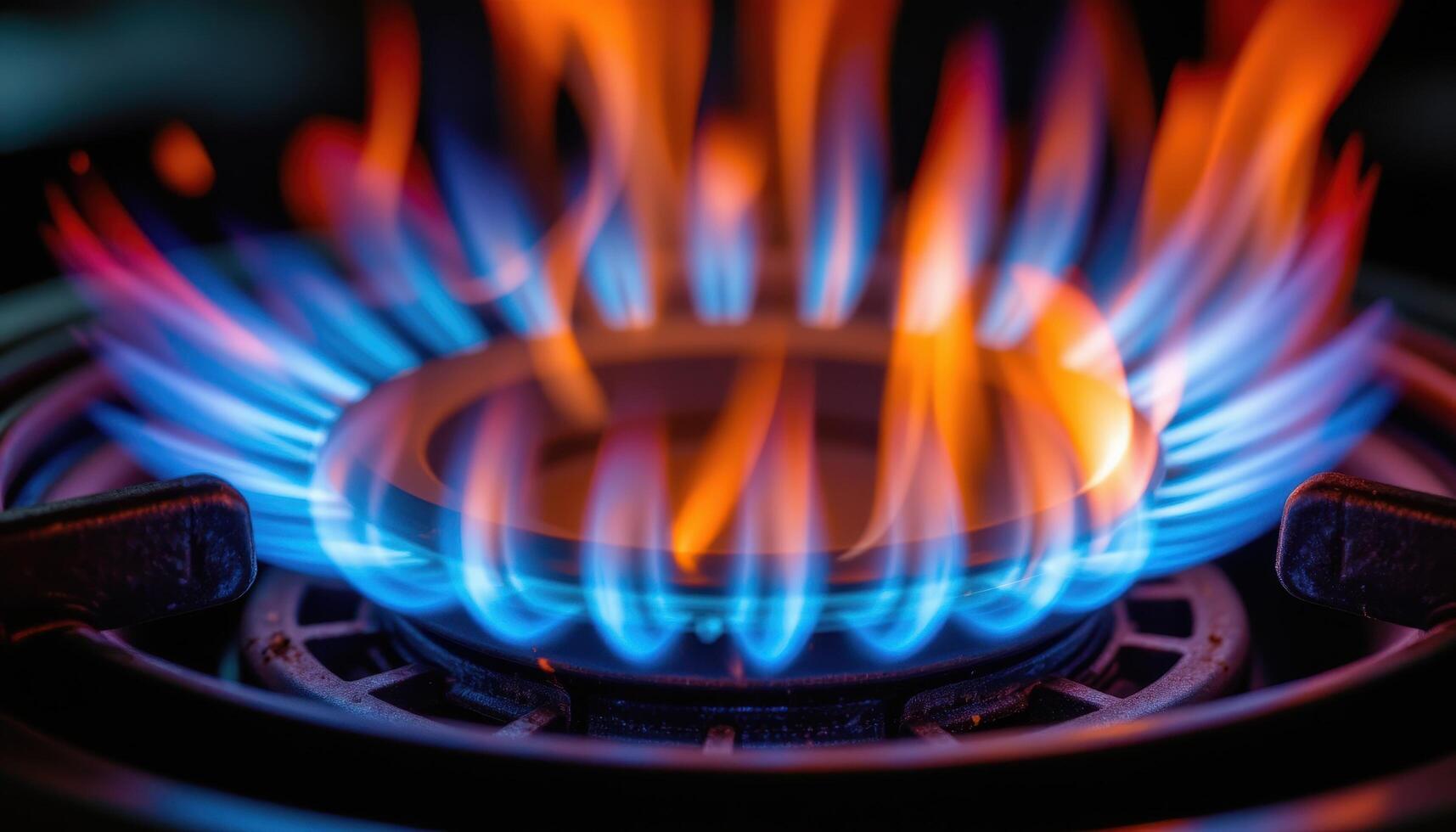 close up view of blue tinted flames burning steadily around a propane burner, surrounded by dark metal surfaces reflecting the light. photo