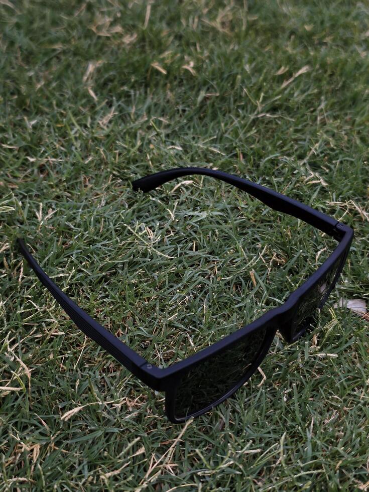 Black sunglasses on green grass summer fashion eyewear style outdoor accessory trendy shades sun protection photo