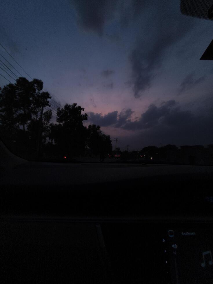 View of twilight sky from car window with clouds and trees silhouette for travel and nature photography photo