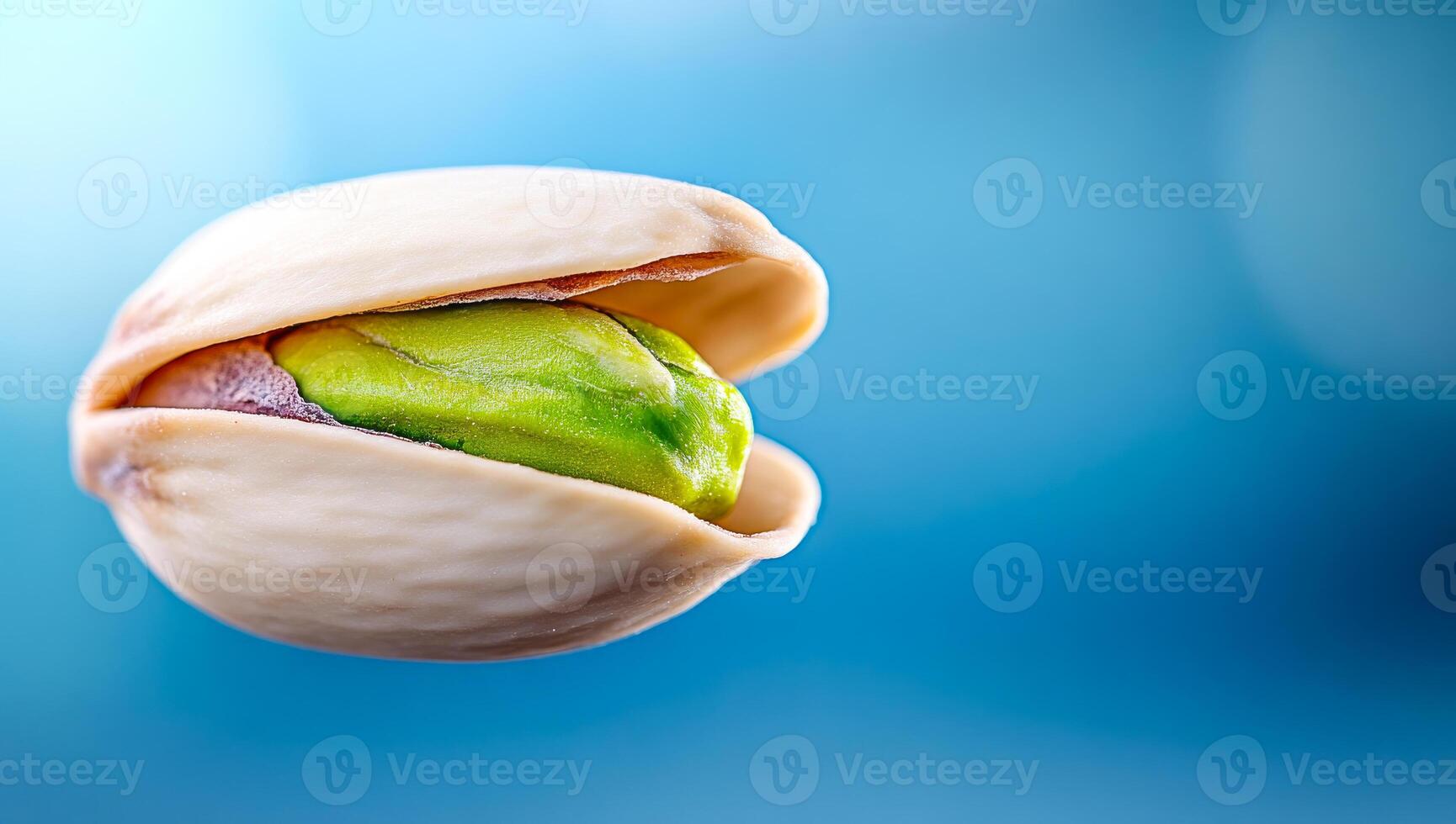 Pistachio nut in shell close-up. A pistachio nut partially opened, revealing its green inner kernel against a soft blue background. photo