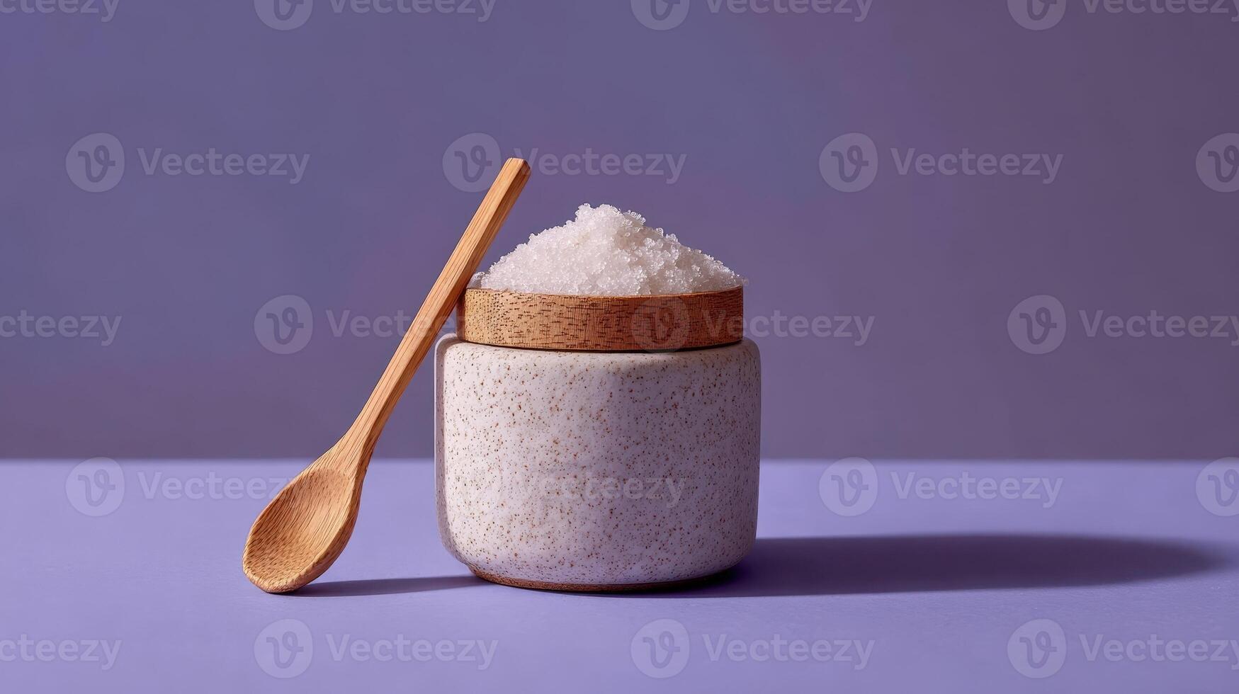 Ceramic jar filled with sugar scrub and wooden spoon placed on a pastel surface for a relaxing self care experience photo