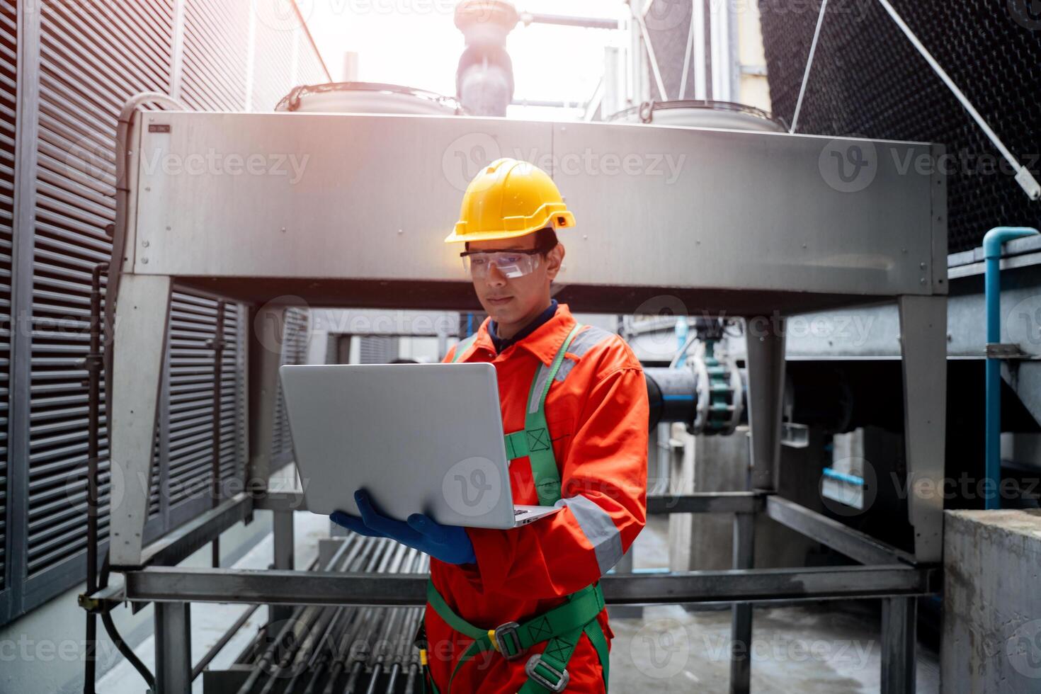 A man in a red and orange jumpsuit is looking at a laptop computer photo