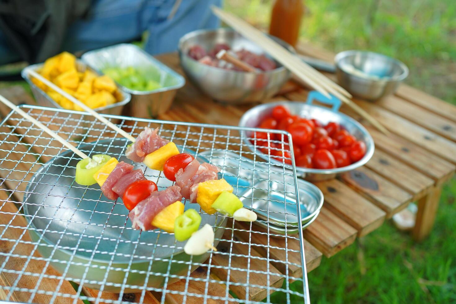 A person is cooking skewers of meat and vegetables on a grill photo