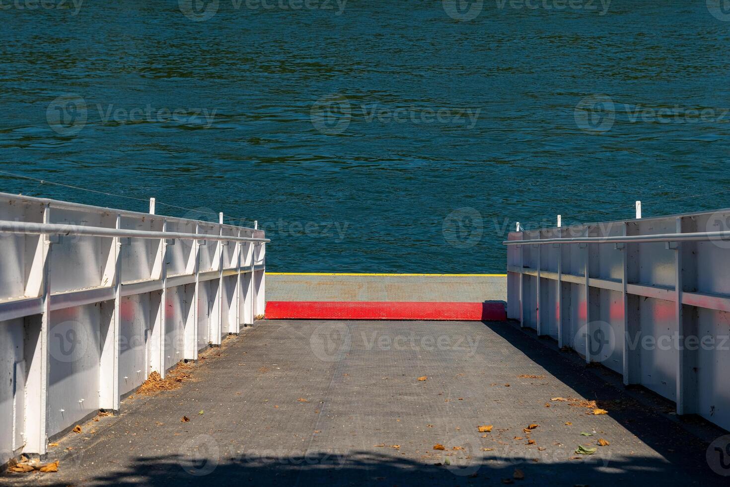 Scenic riverside dock leading to tranquil blue waters at midday under a clear sky in a serene natural setting photo