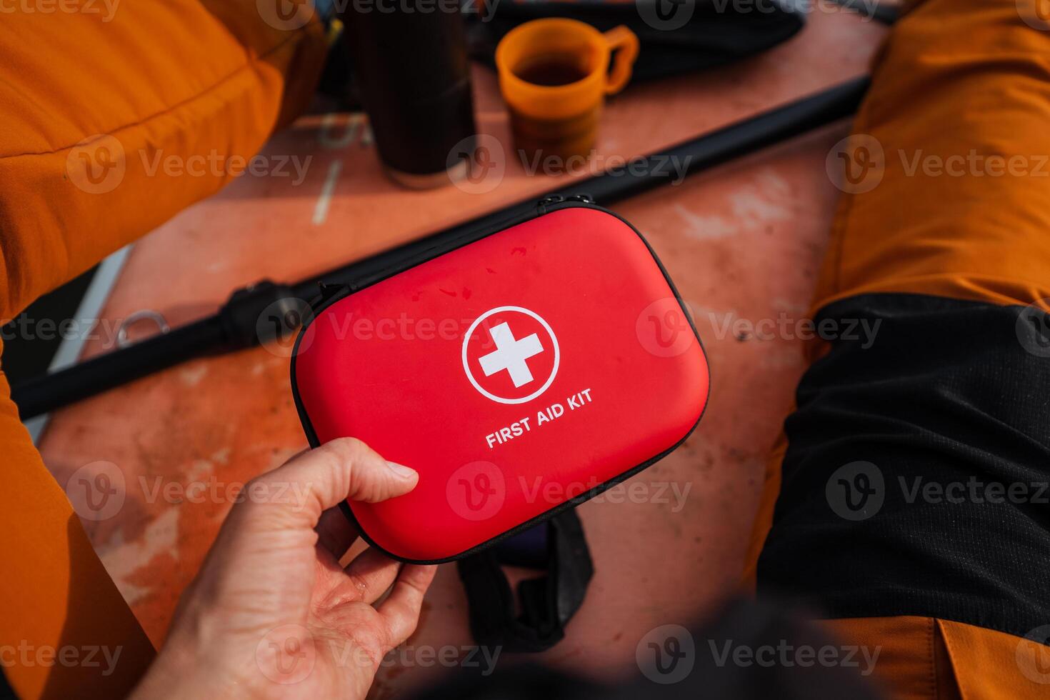 A person is firmly gripping a bright red first aid kit in their hands, fully prepared for any sort of emergency with all the essential medical supplies that are carefully stored inside photo