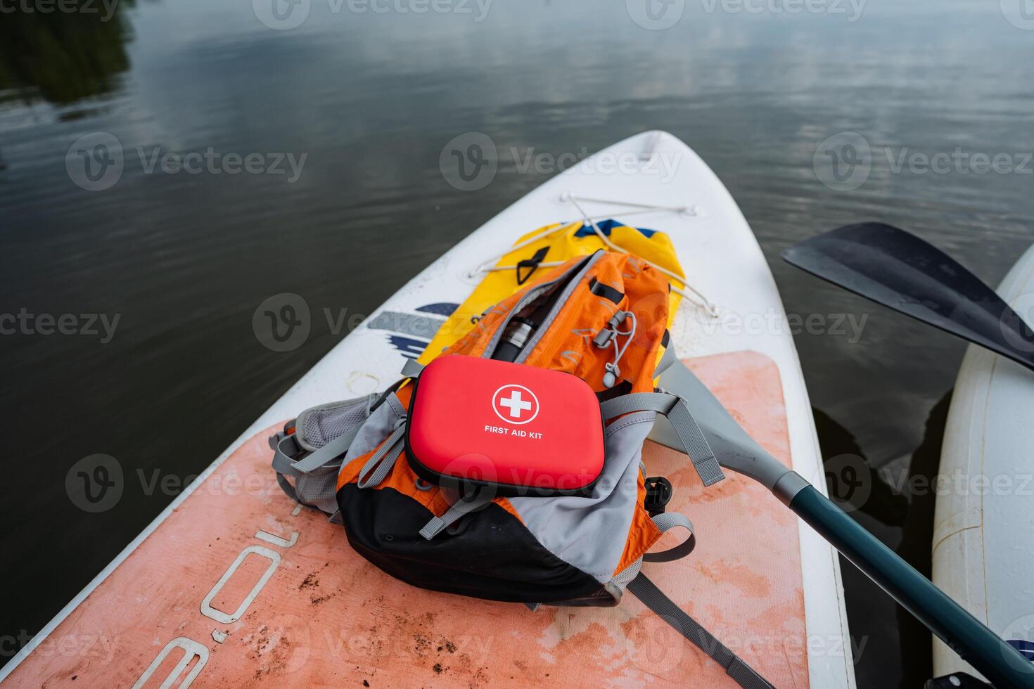 A bright red first aid kit is strategically placed on a paddle board, fully prepared for any emergencies that may arise while enjoying a wonderful time on the water, ensuring safety and fun photo