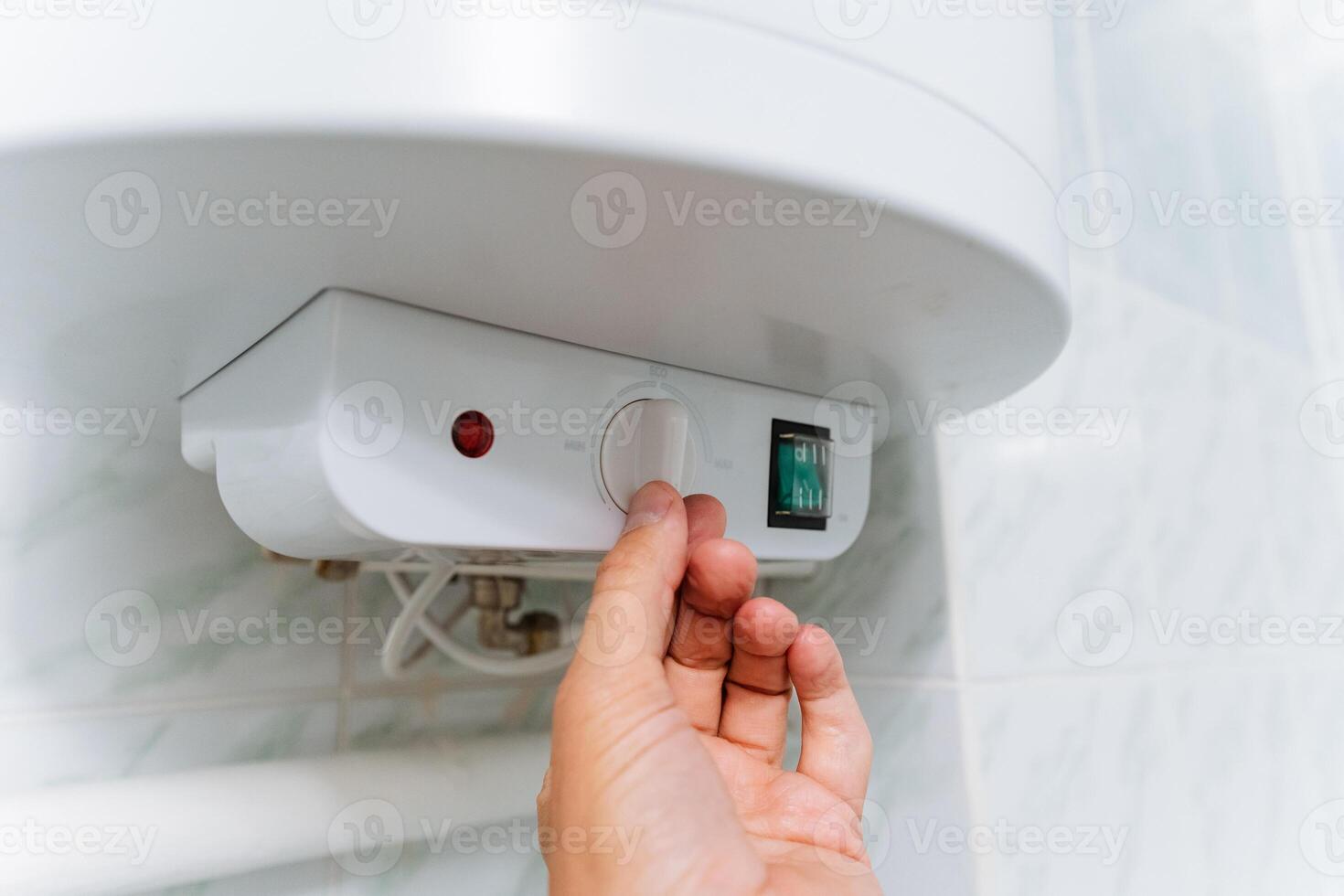 A person is in the process of adjusting the temperature settings of a water heater appliance, ensuring that it operates at the desired level for optimal hot water supply photo