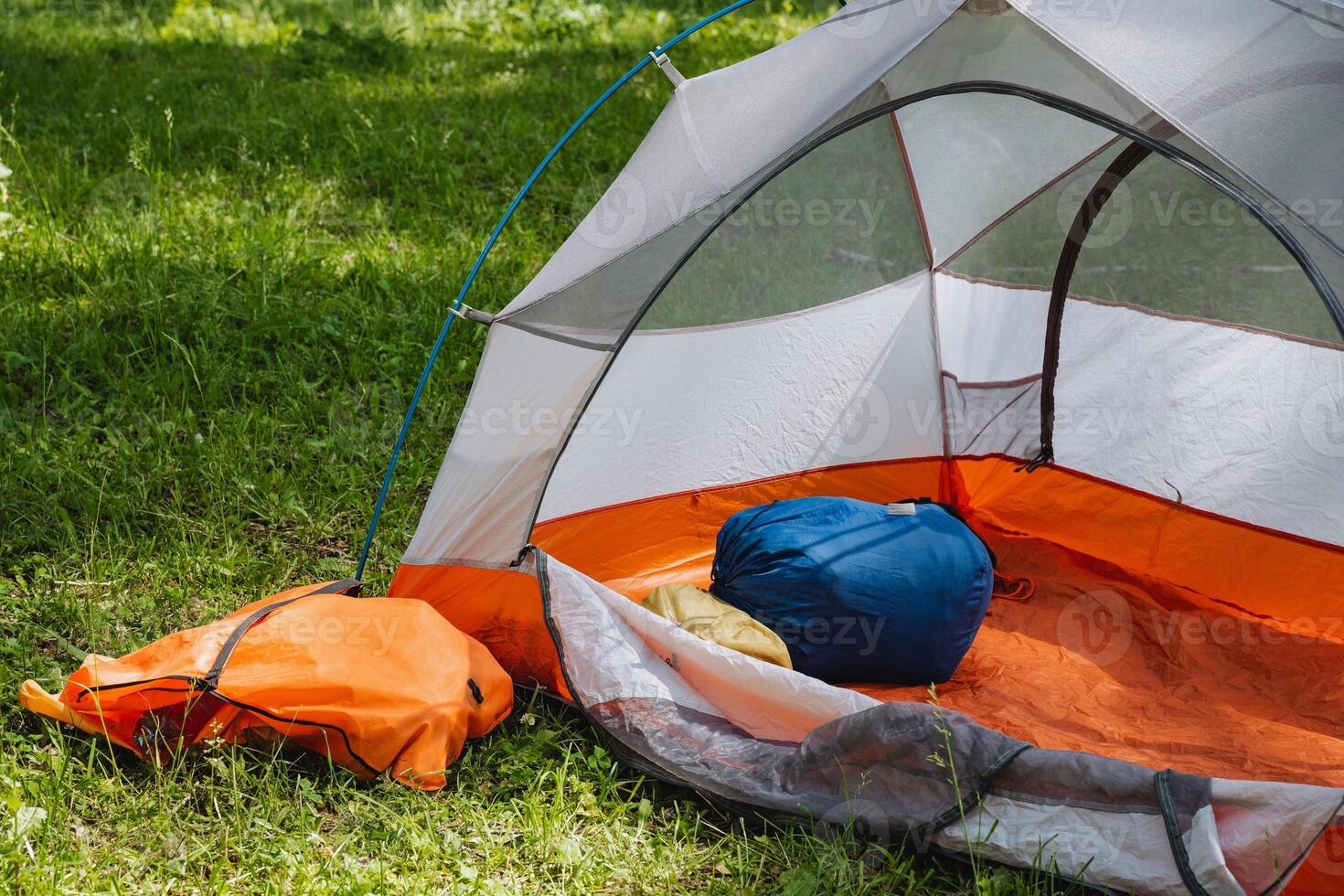 Enjoy a Cozy Camping Tent Setup Nestled on Lush Green Grass with Comfortable Sleeping Gear and all the essentials for a perfect outdoor experience among natures beauty and tranquility photo
