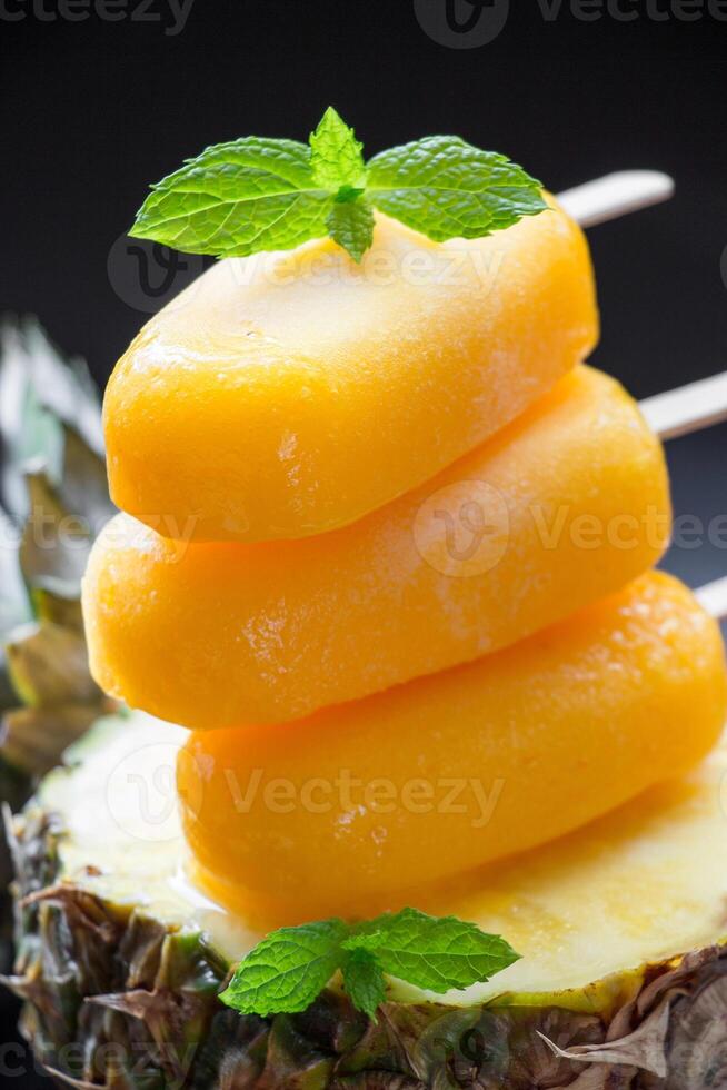 Delight in three vibrant mango pineapple ice cream scoops artfully arranged on a fresh pineapple slice. Each scoop is topped with a touch of mint for a refreshing appeal. photo
