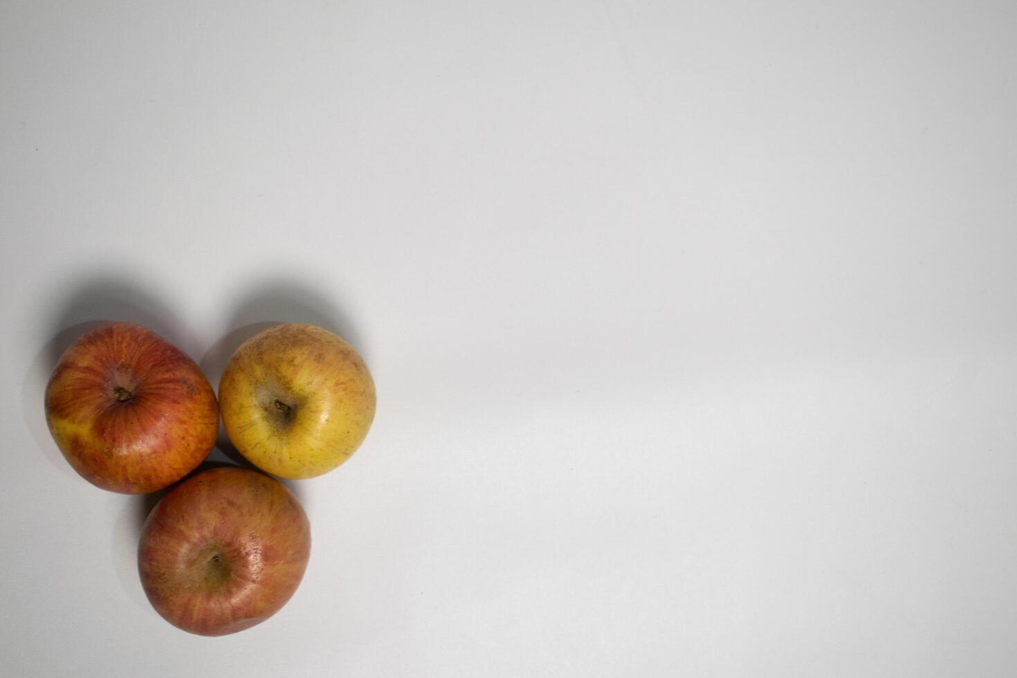 Three apples arranged on a white surface, forming a simple and natural composition. photo