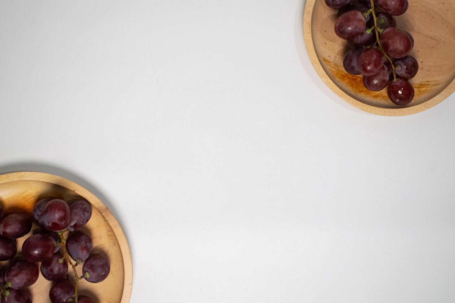 Sweet red grapes on a light wooden plate, perfect for a healthy snack. photo