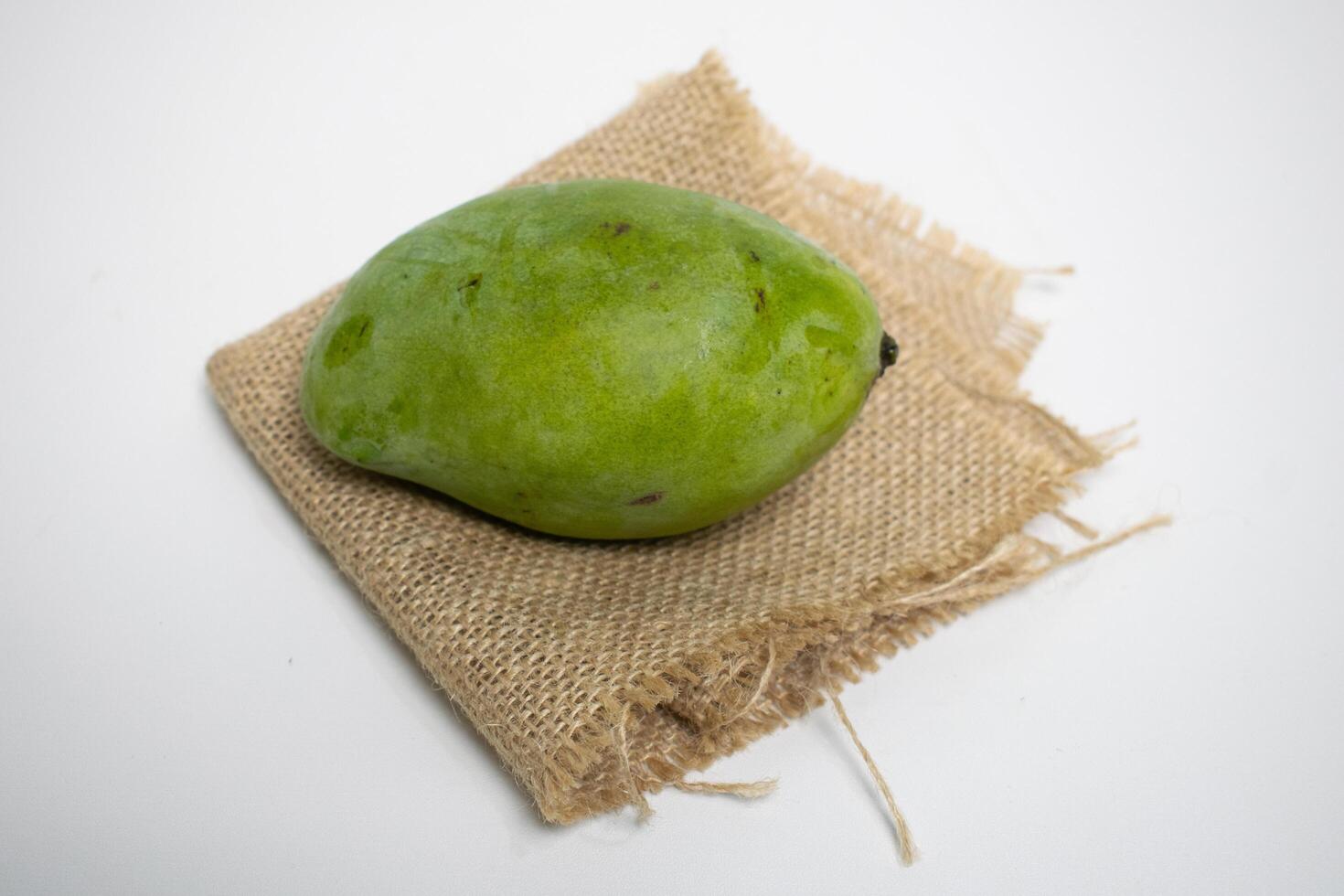 A fresh green mango placed on a piece of rustic burlap cloth, showcasing natural and organic appeal. photo