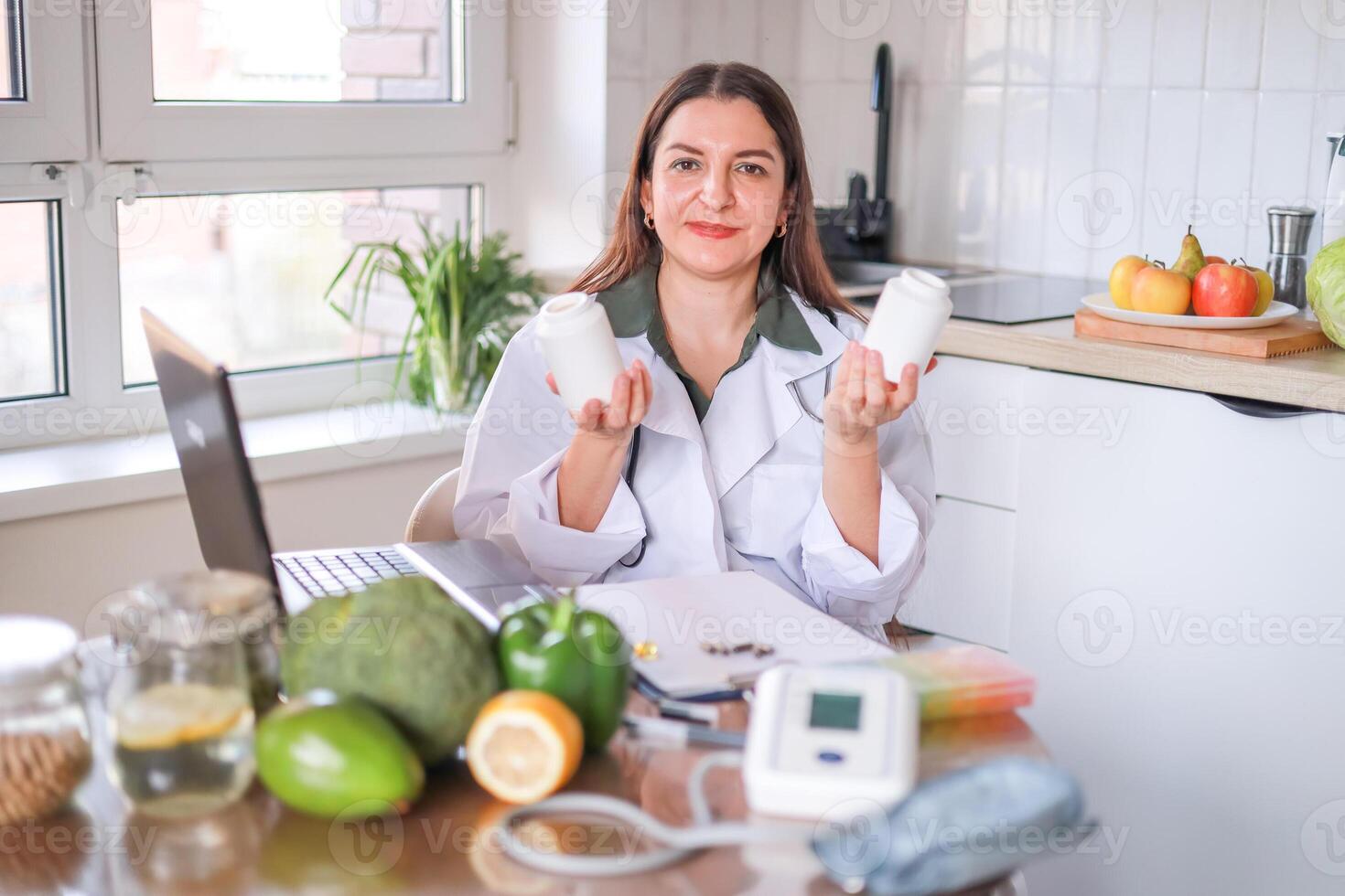 A female nutritionist in a white coat shows jars of dietary supplements against a background of fresh vegetables and fruits. probiotics, vitamin C. Nutrition, health concept. photo