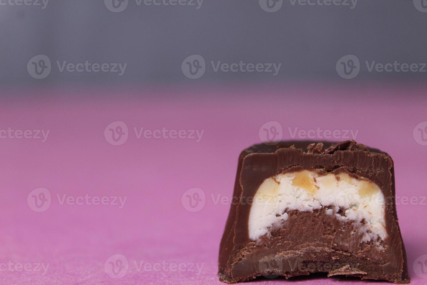 Chocolate candy with praline and pieces of walnut on a pink background close-up with space for copyspace text photo