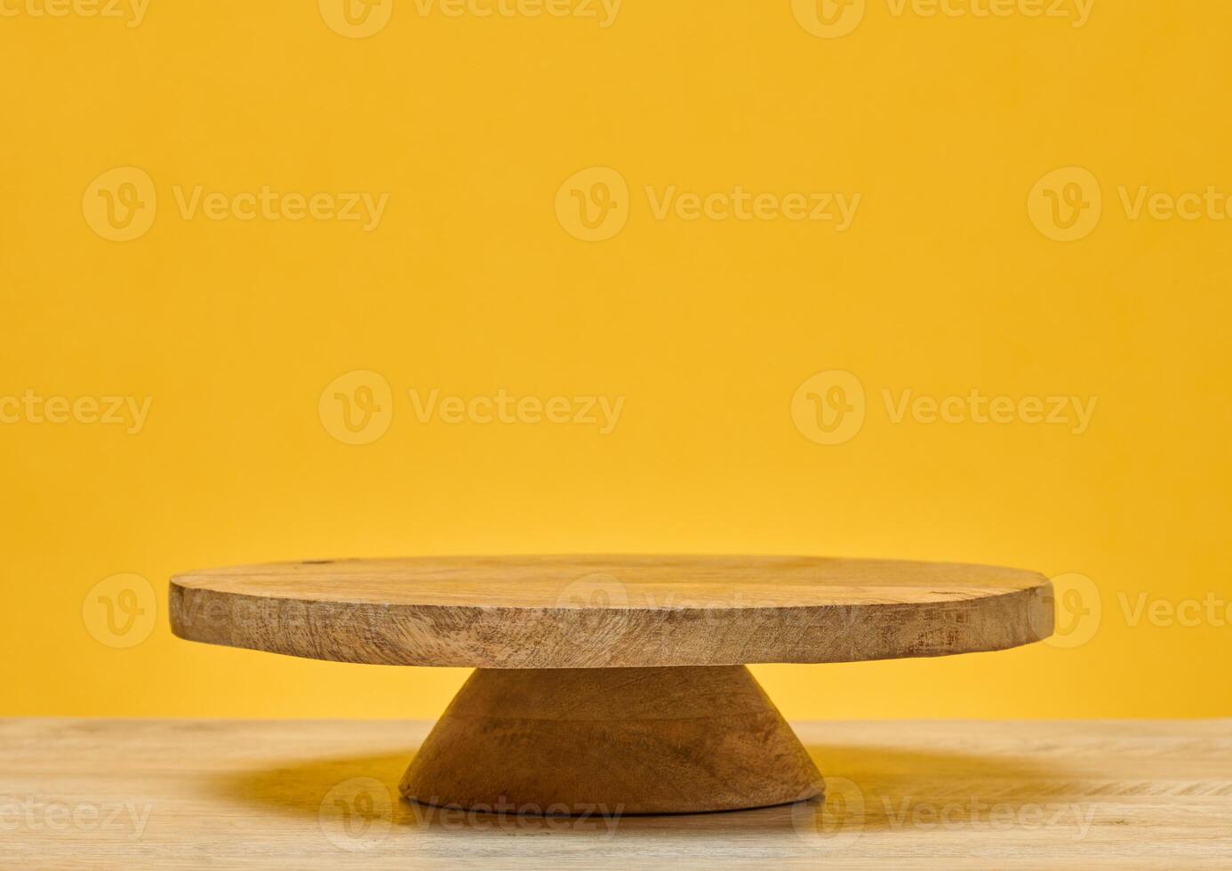 Wooden round podium on wooden table, on bright yellow background. Place for demonstration of products, cosmetics photo