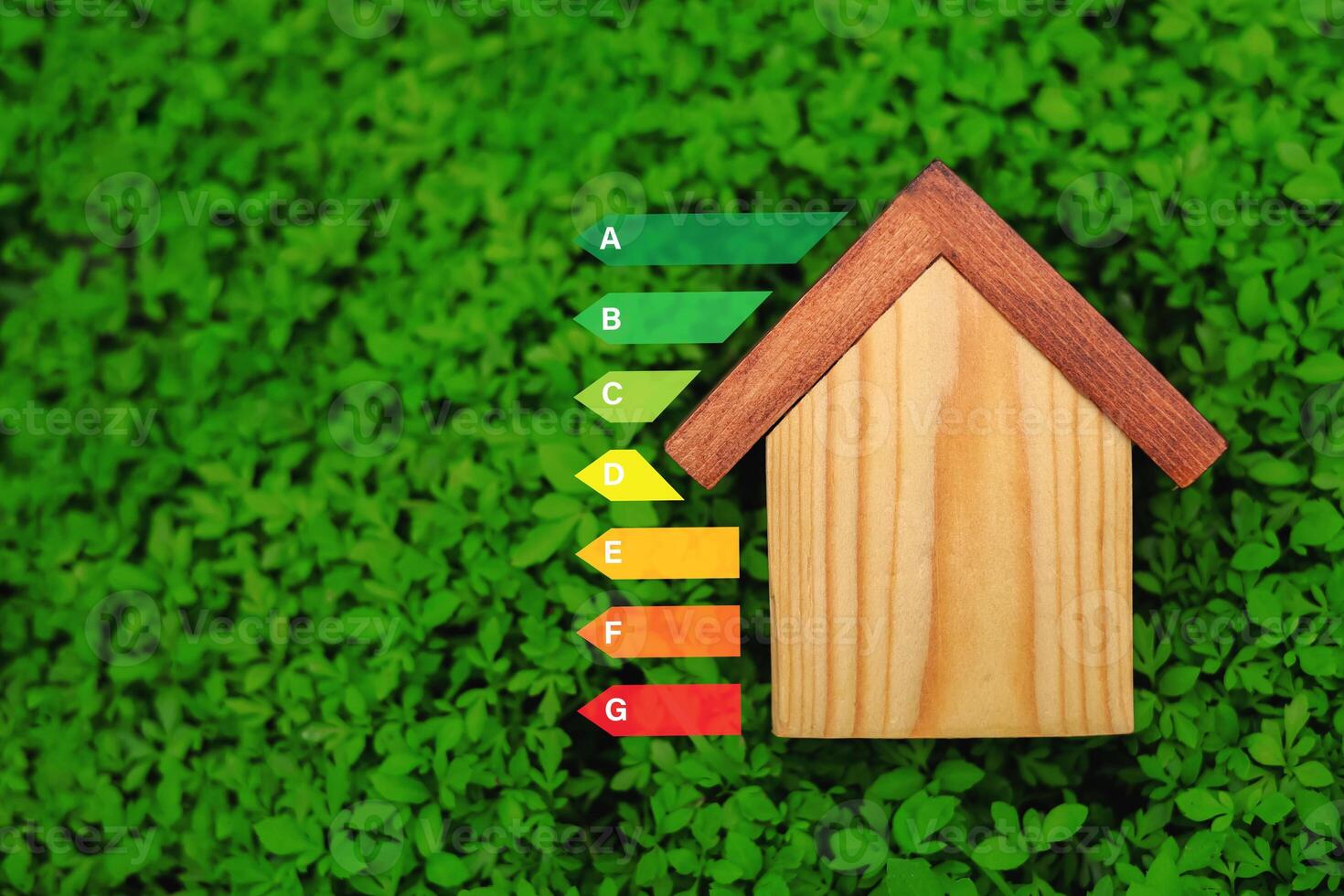 Wooden house on green grass background showing energy efficiency level. Concept of energy saving house, eco friendly home improvement. photo