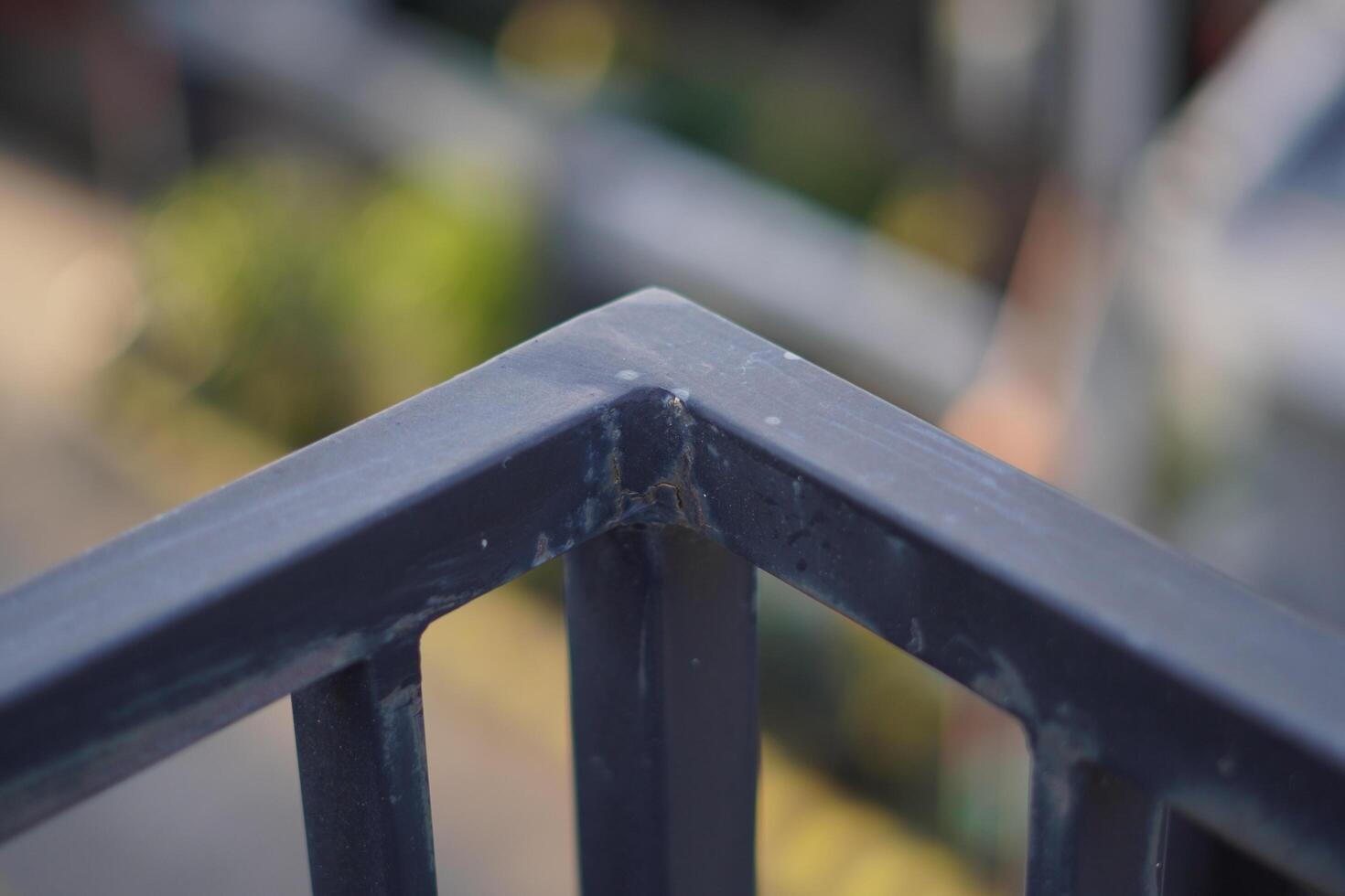 Corner of a black iron fence with blurred background photo