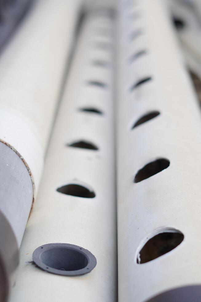 The white tube features round perforations distributed across its surface. photo