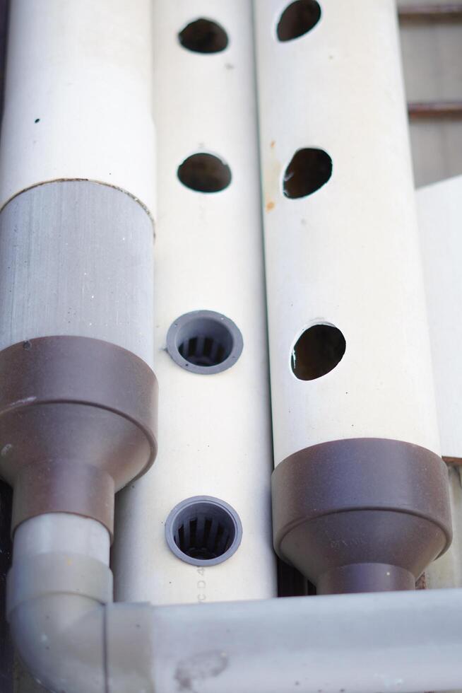 A white pipe runs with circular holes spaced evenly along its length. photo