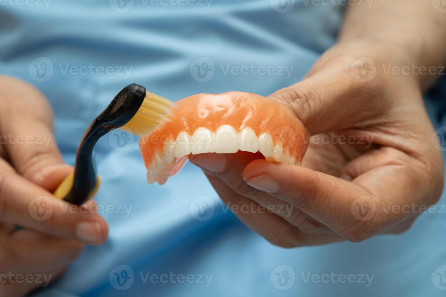 senior woman clean teeth denture with toothbrush for chew food. photo