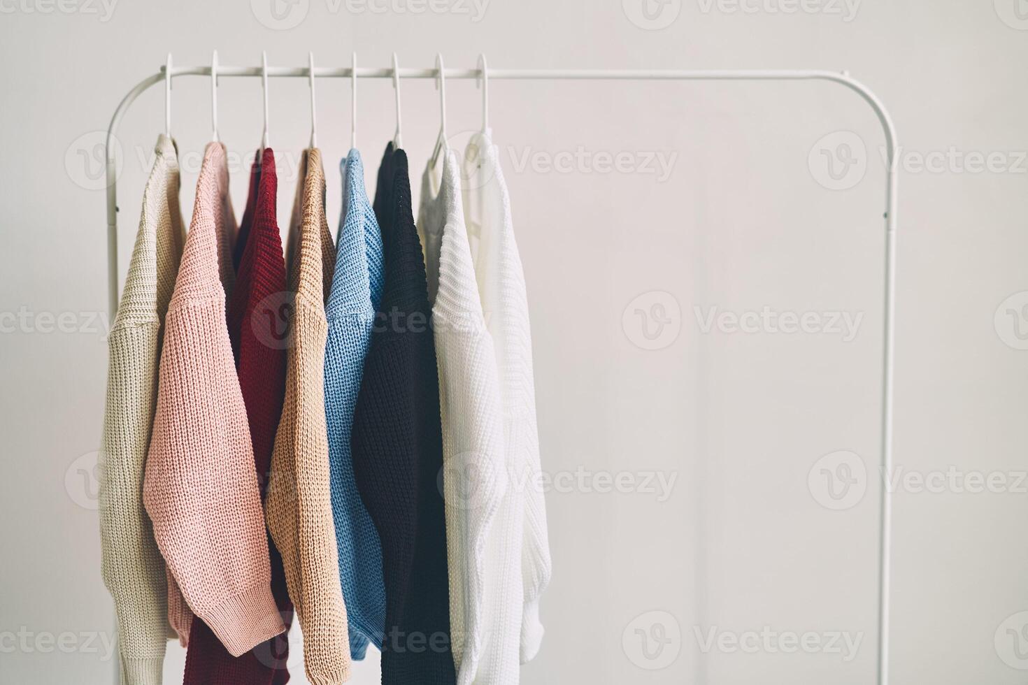 multicolored woolen sweaters on hangers. Sale in a fashion store. photo