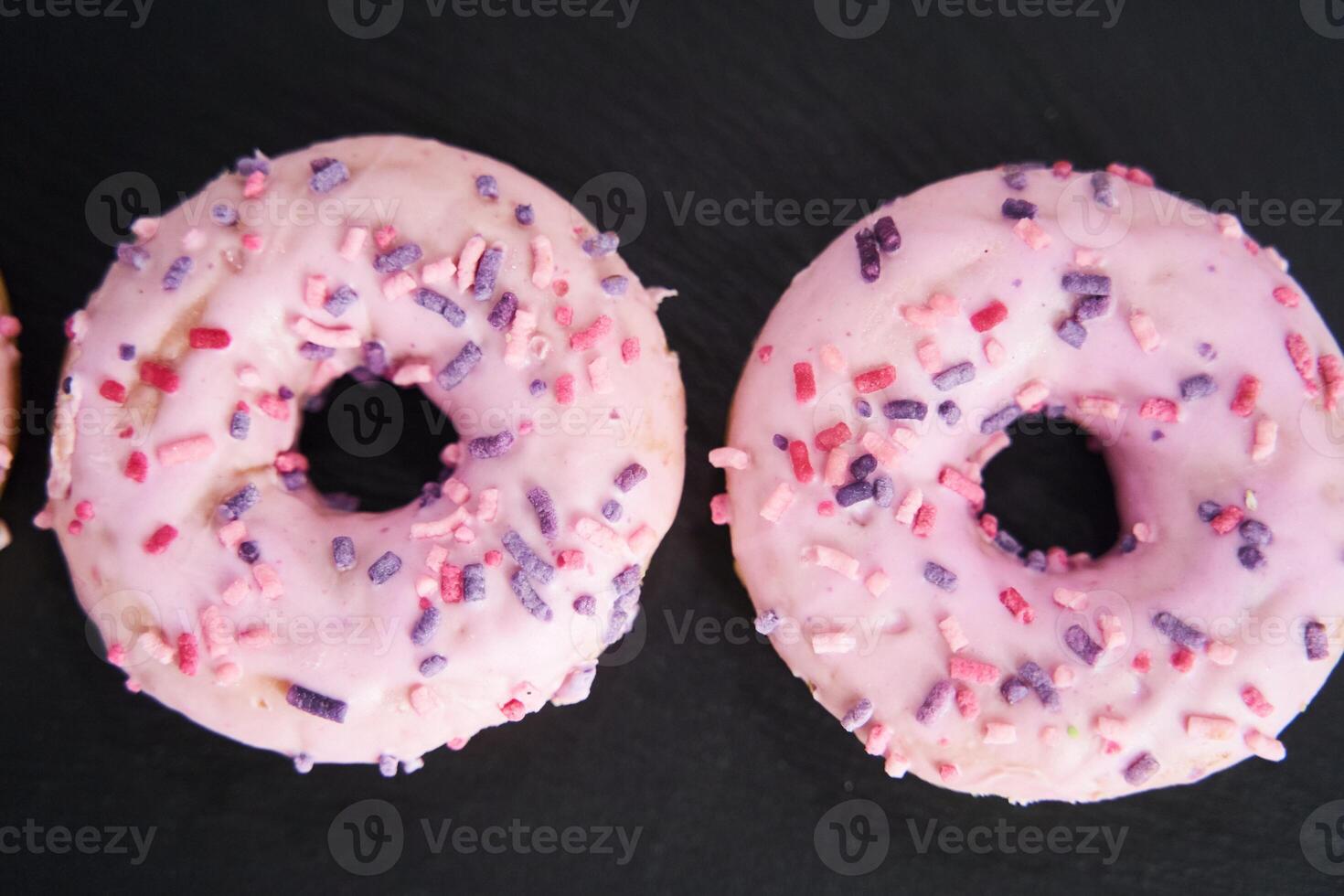 sweet glazed pink donuts close-up on a black tray. photo
