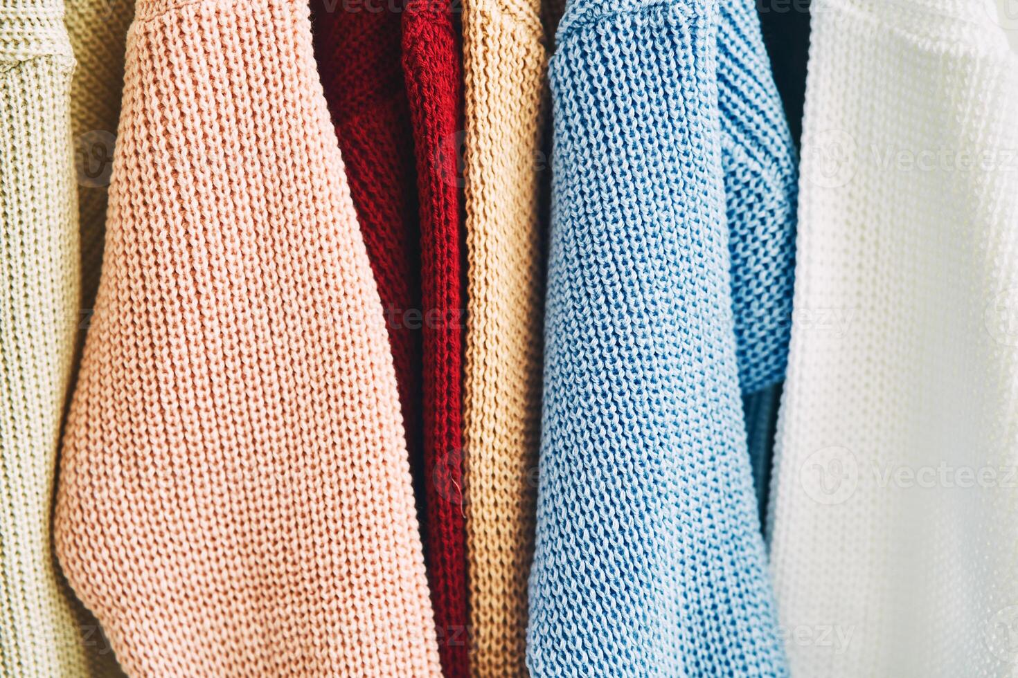 multicolored women's woolen sweaters on hangers. Sale in a fashion store. photo