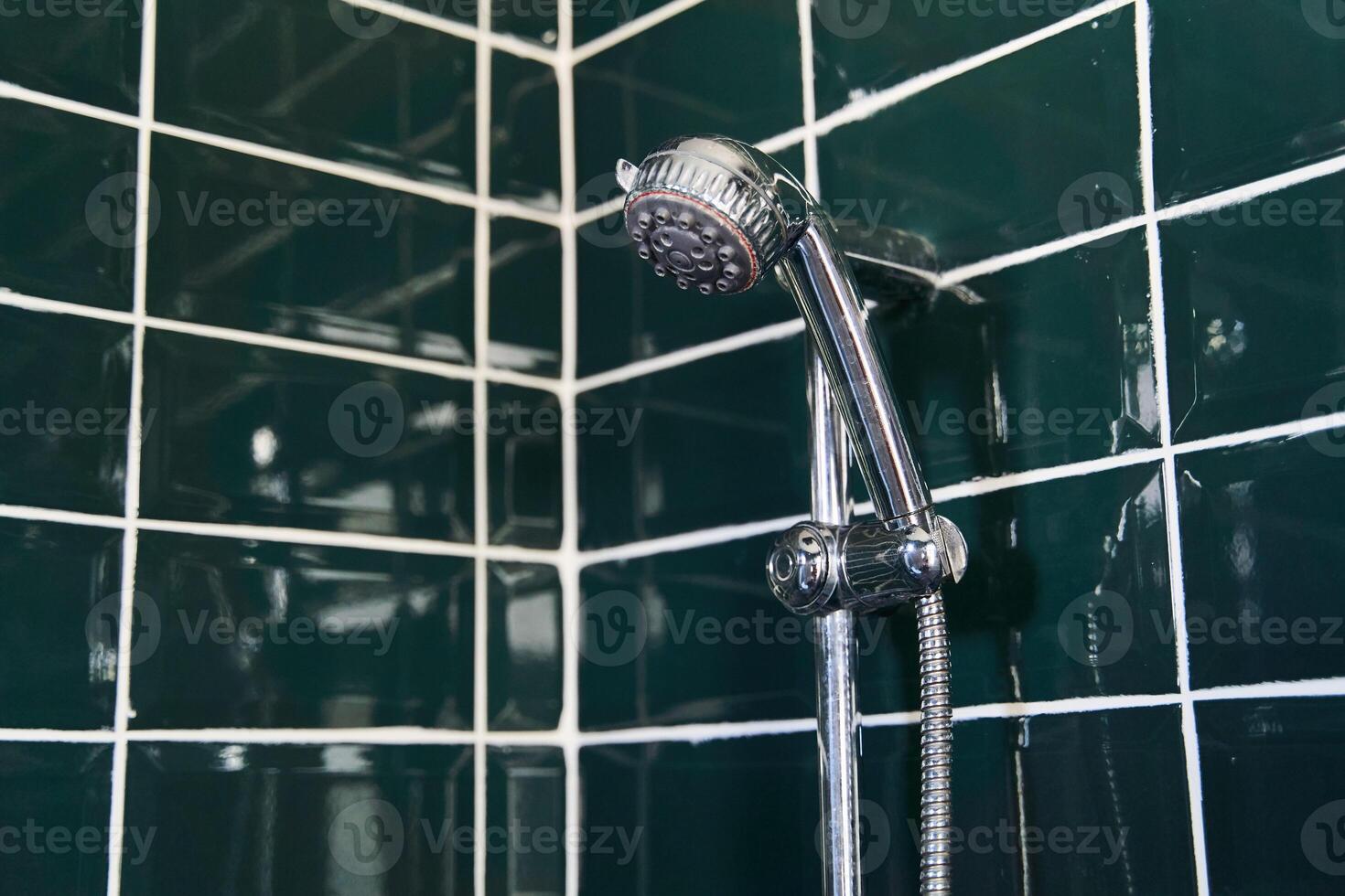 Shower head on a dark green tile background. Stylish modern bathroom interior photo