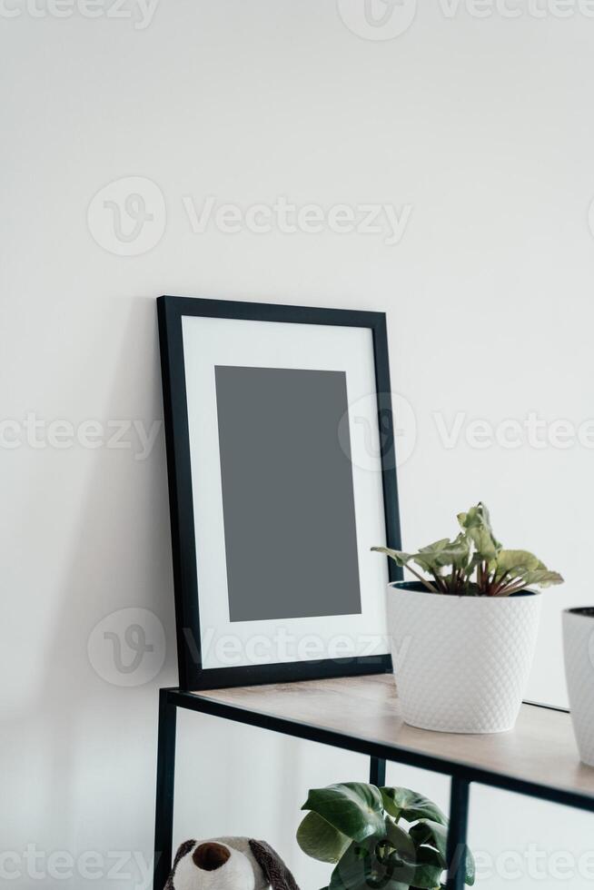 Blank wooden photo frame stands in the interior on a white background.