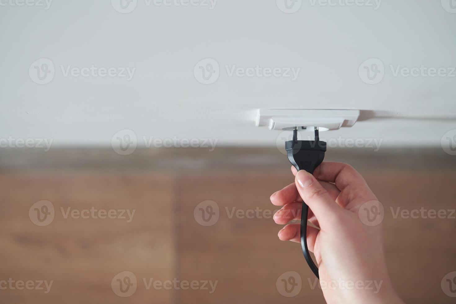 A young girl inserts a plug into an outlet. Young woman plugs the phone charger photo