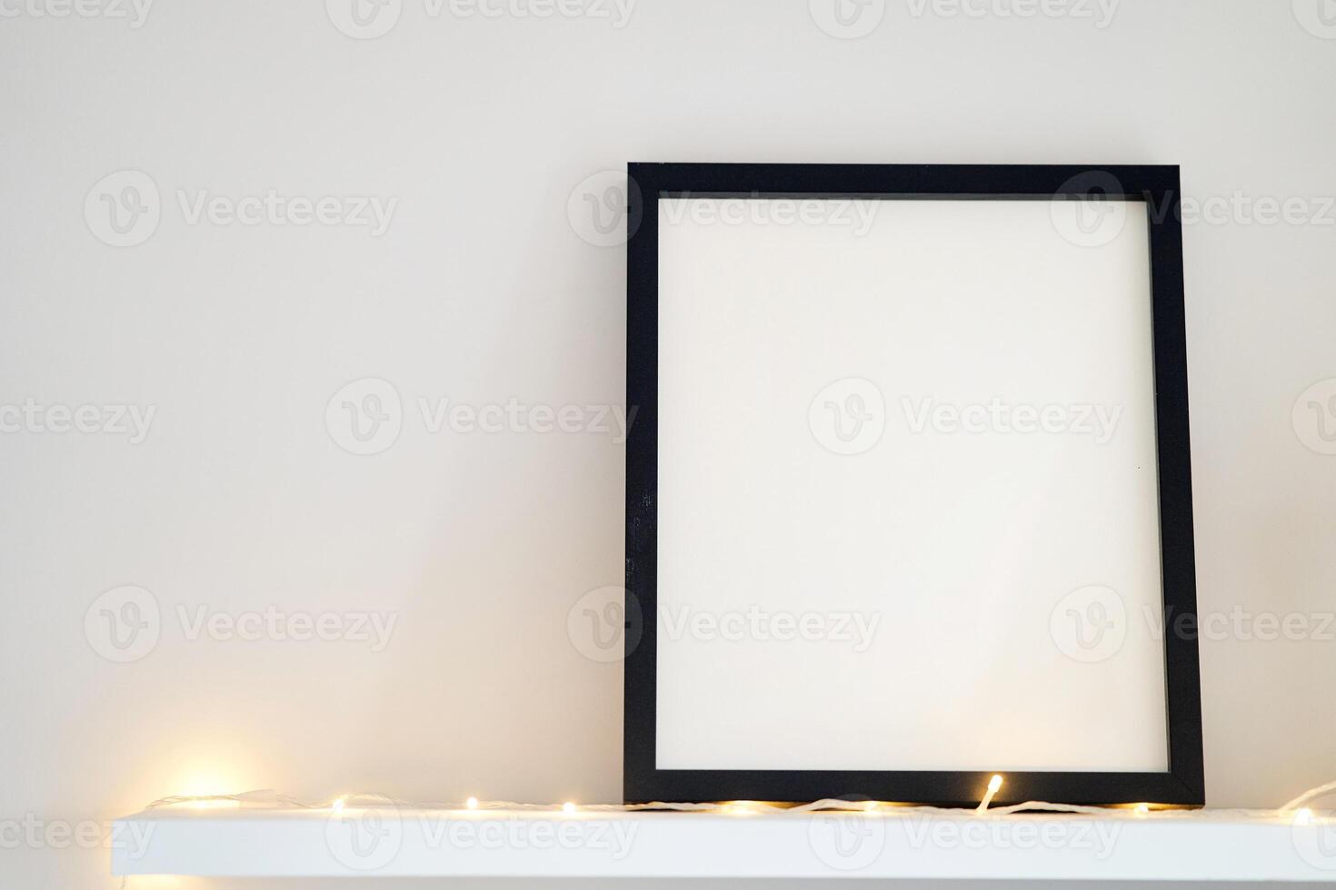 Blank wooden photo frame stands in the interior on a white background. Mockup poster frame close up in home interior.