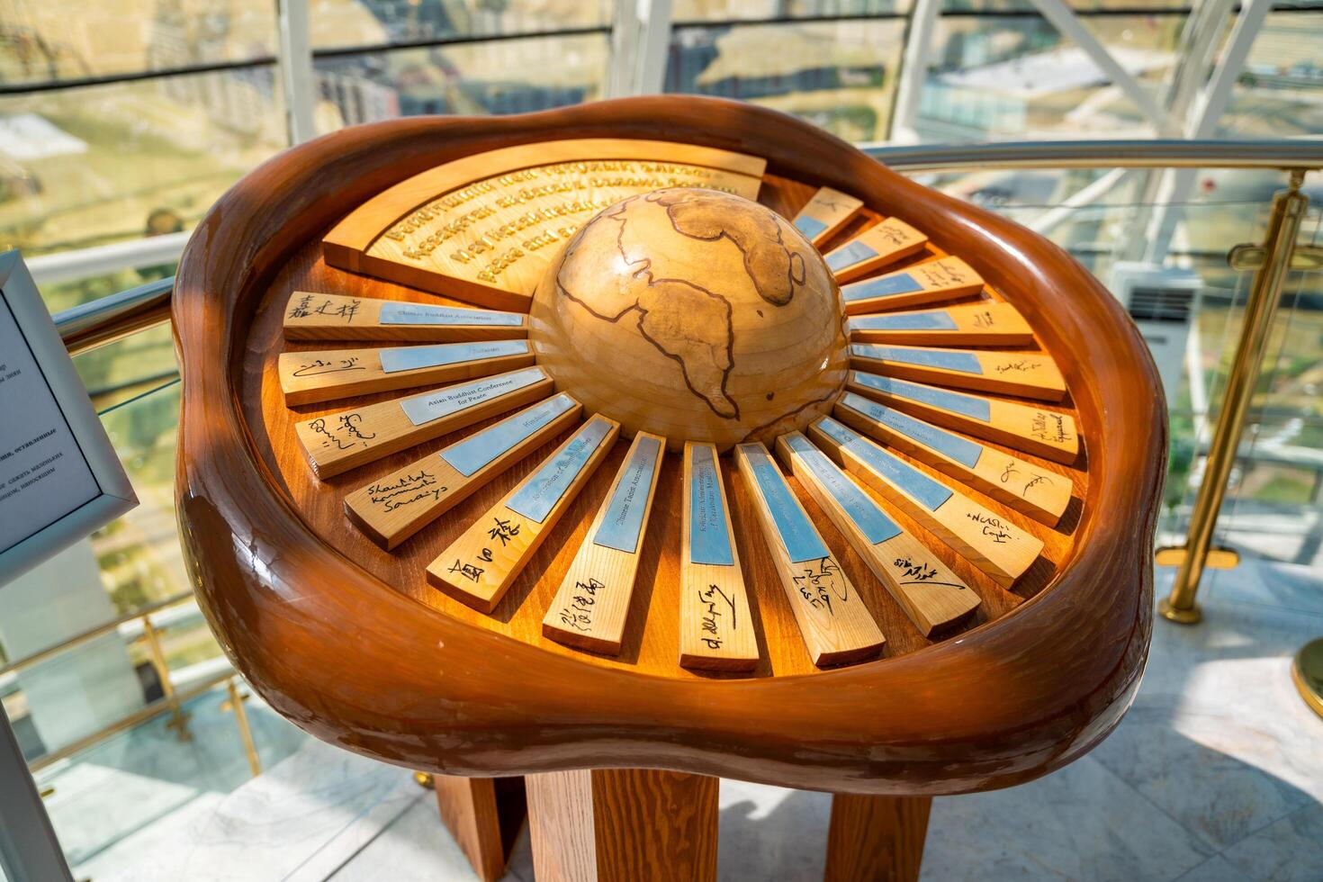 Astana, Kazakhstan - May 21,2025. Wooden globe sculpture with engraved map and nameplates of world leaders displayed in a panoramic observation tower. International cooperation and global diplomacy. photo
