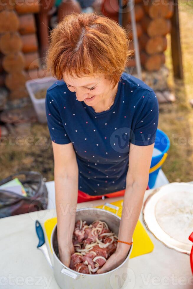 Woman mixing onions and meat with her hands in a bowl while preparing barbecue marinade. Homemade recipe, backyard food prep, and traditional grilling process. High quality photo